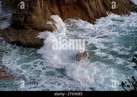 Onde che si infrangono sulle rocce della costa, vista dall'alto onde di superficie del mare sullo sfondo Foto Stock