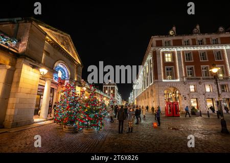 Londra, Regno Unito - 8 novembre 2023: Persone che ammirano gli alberi di Natale e le luci fuori dal mercato di Covent Garden. Foto Stock