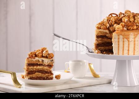 Gocciolatoio al caramello decorato con popcorn e pretzel serviti su un tavolo in marmo bianco Foto Stock