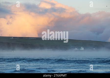 THURSO, SCOZIA-NOVEMBRE 11, 2023. Il vapore sorge da Thurso Bay in una giornata fredda con Holborn Head e Holborn Lighthouse incorniciati da nuvole di tempesta. Foto Stock