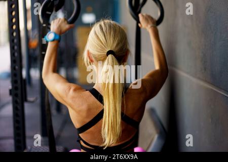 Donna forte che fa esercizi con cinturini da ginnastica fitness in palestra Foto Stock