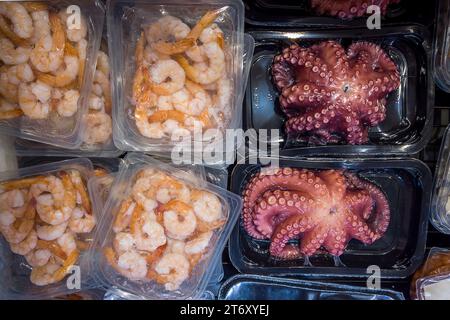 Polpi e gamberetti precotti in vassoi sigillati sottovuoto per cottura sous vide in vendita in banchi refrigerati al supermercato Foto Stock