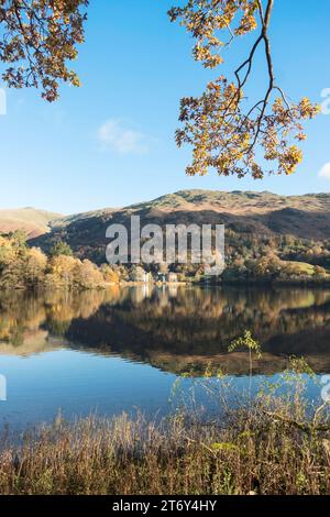 Vista autunnale del lago Grasmere, con le colline che si riflettono nell'acqua, Cumbria, Inghilterra, Regno Unito Foto Stock