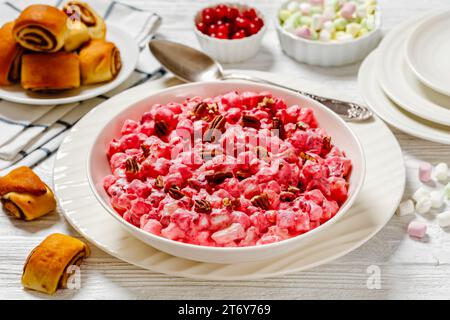 insalata cremosa di mirtilli rossi con mini marshmallow, mela fresca e noci pecan in ciotola bianca su tavolo di legno bianco con dolci alla cannella, ricetta americana, h Foto Stock