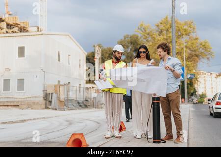 Architetti e ingegneri analizzano i progetti, discutono la pianificazione e i costi dei progetti e collaborano a un design urbano innovativo in un ambiente aziendale. Foto Stock