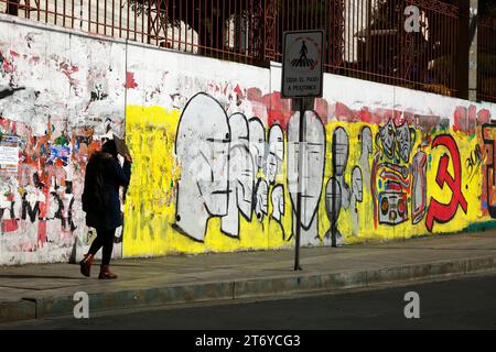 Una donna passeggia davanti a un murale del Partito Comunista Boliviano vicino alla principale università UMSA nel centro di la Paz, in Bolivia Foto Stock