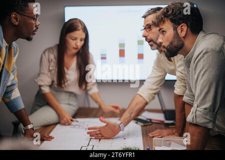 Professionisti diversificati collaborano in una moderna riunione d'ufficio. Discutono di progetti architettonici, dimostrano il lavoro di squadra. Foto Stock