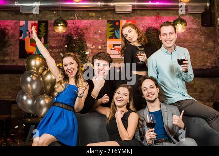 Ritratta le giovani coppie sorridenti con un bicchiere di vino che si divertono a fare festa Foto Stock