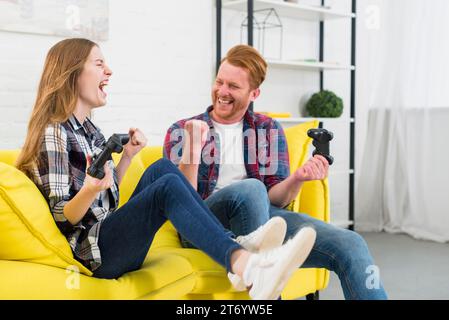 Ritrarre giovani coppie entusiaste che si divertono a giocare a casa ai videogame Foto Stock