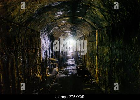 Vecchio tunnel fognario sommerso sotterraneo a volta scura. Foto Stock