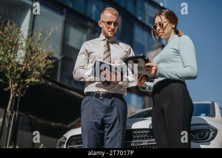 Diversi team aziendali collaborano a progetti di espansione aziendale all'aperto, discutendo le tendenze del mercato, la pianificazione finanziaria e la crescita dei ricavi. Foto Stock