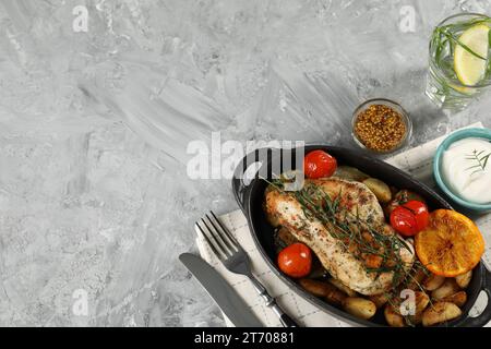 Pollo gustoso, verdure, bevanda con dragoncello e condimenti per insalata serviti su un tavolo grigio, piatti. Spazio per il testo Foto Stock