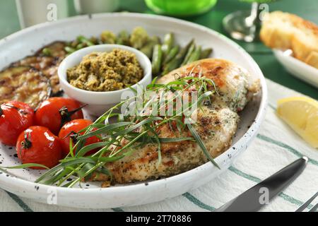 Pollo gustoso, verdure con dragoncello e pesto serviti al tavolo, primo piano Foto Stock