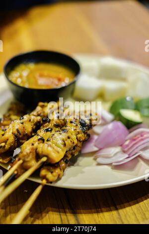 Spiedini di satay di pollo con cipolla rossa, fette di cetriolo e torte di riso e salsa di arachidi al Limapulo: Baba CAN Cook, un ristorante Peranakan Foto Stock
