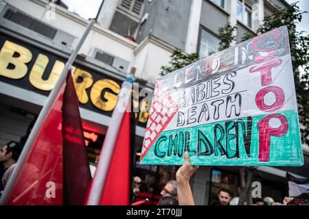 Istanbul, Turchia. 12 novembre 2023. Tra i manifestanti in marcia che si avvicinavano a Sultanahmet, una persona è stata vista con in mano uno striscione che diceva "genocidio bambini morte bambini fermi" mentre passava davanti a Burger King. La Palestine Initiative Platform ha formato una catena umana da Edirnekapi a Sultanahmet per protestare contro gli attacchi israeliani a Gaza. Credito: SOPA Images Limited/Alamy Live News Foto Stock