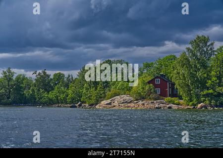 Una pittoresca scena rurale con una casa affascinante situata su una piccola isola in un lago tranquillo. Foto Stock