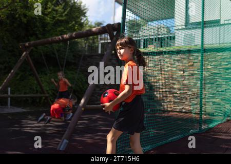 Fratelli che giocano a calcio, vestiti con maglie da calcio. La famiglia come una sola squadra di calcio. Attività sportive per famiglie all'aperto nel cortile sul retro o sul Foto Stock