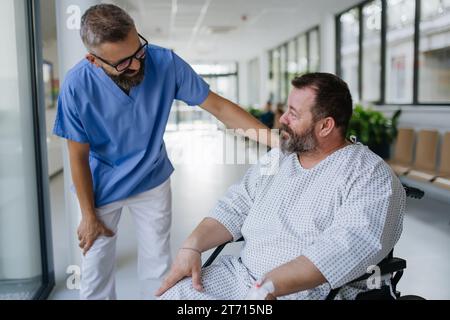 Primo piano del medico di supporto che parla con un paziente in sovrappeso preoccupato in sedia a rotelle. Malattie e malattie nella salute degli uomini di mezza età. Compassionevole Foto Stock