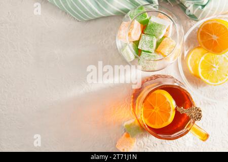 Dolcezza orientale: Delizia turca e tè con tavolo bianco limone con un motivo, vista dall'alto. Le ciotole contengono dolci e limone a fette. In una trasposizione Foto Stock