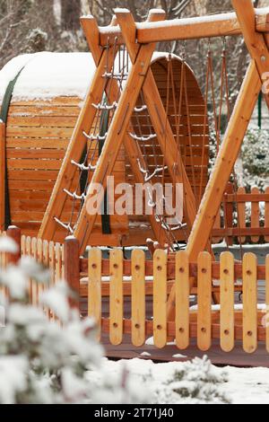 Altalene di legno, scale, casa, auto sul parco giochi. Parco giochi per bambini in inverno. Foto Stock