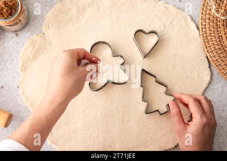 Le mani femminili tagliano forme e preparano biscotti di Natale. Foto Stock