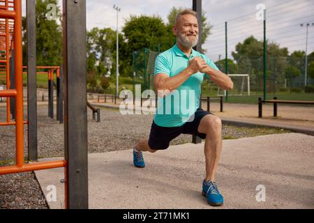 Un anziano che fa degli esercizi fisici in campo sportivo all'aperto Foto Stock