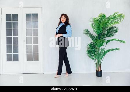 una donna si trova in una stanza luminosa con un fiore decorativo verde Foto Stock