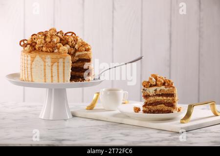 Gocciolatoio al caramello decorato con popcorn e pretzel serviti su un tavolo in marmo bianco Foto Stock