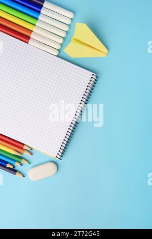 Composizione piatta con notebook aperto e altra cancelleria scolastica su sfondo azzurro, spazio per testo. Torna a scuola Foto Stock