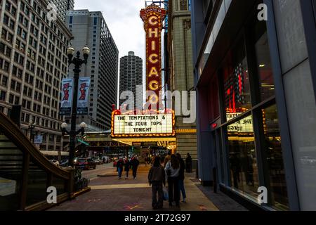 Il cartello verticale "Chicago" del Chicago Theatre brilla sopra State Street nel Loop, Chicago, Illinois, Stati Uniti, il suo tabellone sotto annuncia una performance congiunta dei Temptations e dei Four Tops quella sera. sullo sfondo si ergono le torri gemelle cilindriche di Marina City, soprannominate "pannocchie" per la loro forma. Aperto nel 1921 in uno stile barocco revival francese dagli architetti Cornelius e George Rapp, il teatro ha una capienza di 3.600 posti. Foto Stock
