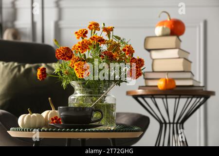 Splendidi fiori autunnali, una tazza di bevande e zucche sul tavolino al chiuso, spazio per il testo Foto Stock