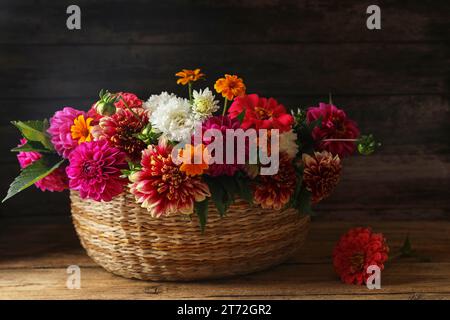 Bellissimi fiori selvatici e foglie in cesto di vimini su un tavolo di legno Foto Stock