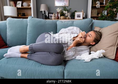Giovane donna triste e depressa sdraiata sul letto che odora la camicia dei fidanzati, sentendosi infelice le manca e lui è un soldato militare o malato all'hospit Foto Stock