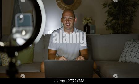Giovane ispanico che registra video giocando a un videogame seduto sul divano a casa Foto Stock
