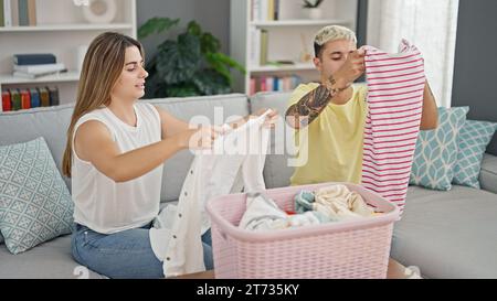 Bella coppia seduto sul divano con vestiti pieghevoli a casa Foto Stock