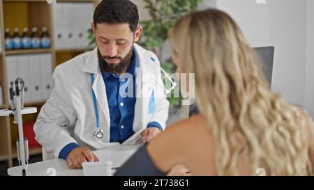 Giovane medico ispanico che misura il polso del paziente utilizzando il tensiometro a braccio presso la clinica Foto Stock