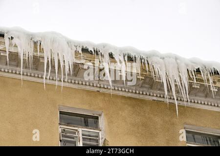 Enormi pezzi di ghiaccio appesi alle grondaie di edifici che minacciano di crollare durante il disgelo Foto Stock