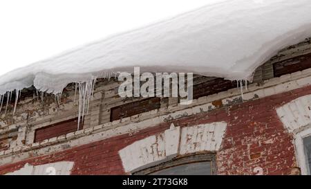 Un enorme blocco di neve pende pericolosamente dall'edificio karziz, pronto a rompersi e cadere. Foto Stock