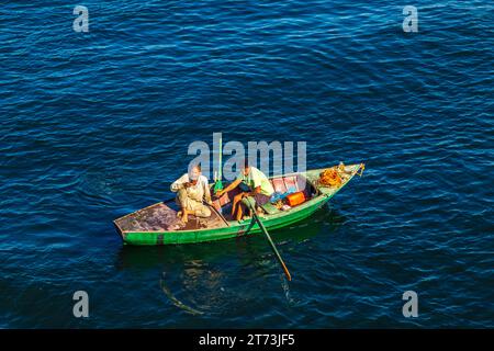 I venditori di tessuti sulle loro barche si avvicinano a una nave da crociera in attesa di entrare nella chiusa di Esna. I venditori sperano di vendere beni ai turisti. Esna, Egitto – 20 ottobre Foto Stock