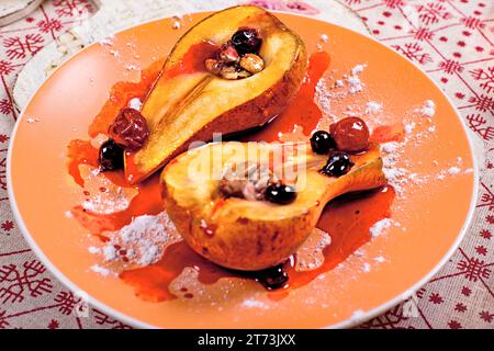 Due fette di pera al forno ripiene di noci e frutti di bosco sotto marmellata di fragole. Foto Stock