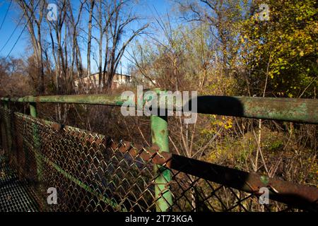 Ponte pedonale verde arrugginito sul fiume. Foto Stock