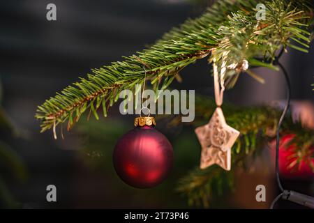 Una palla rossa e una stella su un albero di Natale tagliato per Natale Foto Stock