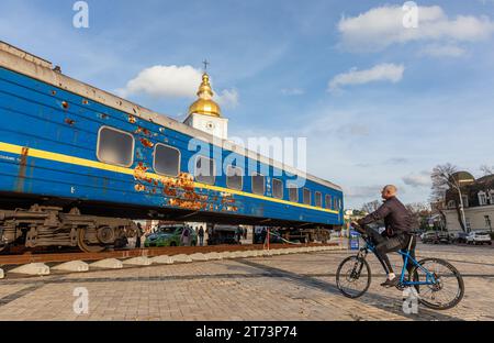 Kiev, Ucraina. 10 novembre 2023. Un uomo in bicicletta è visto mentre guarda una carrozza ferroviaria Ucraina uccisa dalle truppe russe in piazza Mykhailivska a Kiev. Il carro di bombardamento è stato installato nel centro di Kiev in Piazza Mykhailivska in occasione della giornata dei lavoratori ferroviari. Fa parte del treno di evacuazione che ha evacuato le persone da Irpen, nella regione di Kiev, all'inizio della guerra su vasta scala. Il treno fu sotto il fuoco delle truppe russe mentre portava i civili fuori da Irpin. Oggi, il carro è diventato un simbolo di indistruttibilità. (Immagine di credito: © Mykhaylo Palinchak/SOPA Images via ZUMA Press Wire Foto Stock