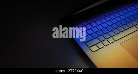 primo piano della tastiera di un computer portatile su un tavolo scuro con riflesso della luce colorata. striscione con spazio per la copia Foto Stock