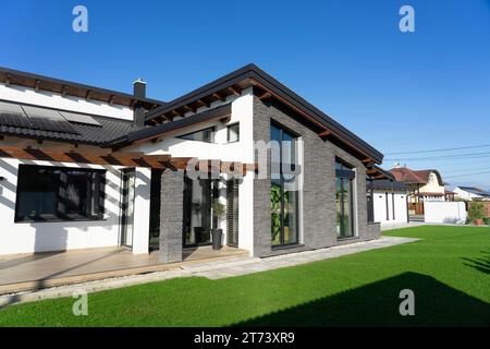 Casa moderna con pareti in pietra grigia e pareti bianche in un giardino con fresco gras verde. Foto Stock