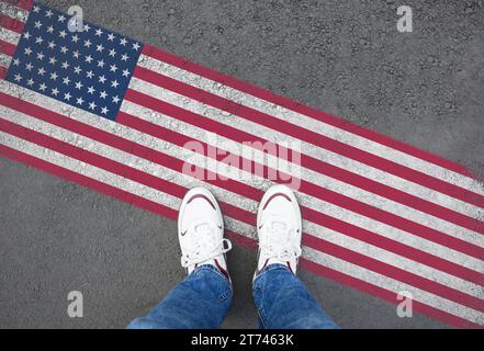 Immigrazione. Uomo in piedi su asfalto vicino alla bandiera degli Stati Uniti, vista dall'alto Foto Stock