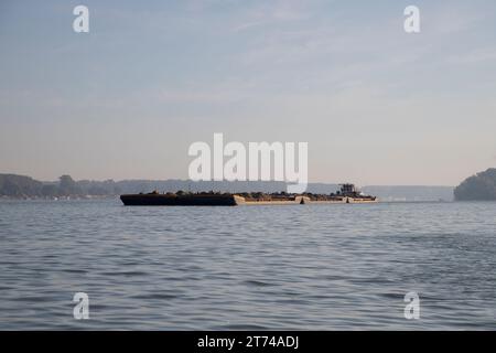 Un rimorchiatore spinge chiatte combinate caricate di sabbia lungo il Danubio Foto Stock