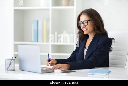 Donna d'affari di successo che lavora su un notebook in ufficio Foto Stock