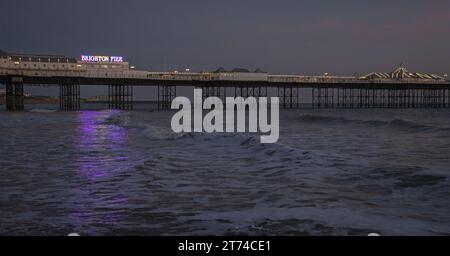 Vedute lontane del Palace Pier illuminato di notte da Brightons che si riflette sull'acqua, Brighton, Sussex, Inghilterra, Regno Unito Foto Stock