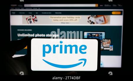 Persona che possiede un cellulare con il logo del servizio di abbonamento Amazon prime davanti alla pagina Web aziendale. Concentrarsi sul display del telefono. Foto Stock